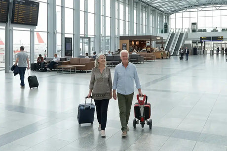 Pareja camina por la terminal de un aeropuerto llevando el scooter esla plegable tipo trolley de forma cómo da y ligera dortomedical