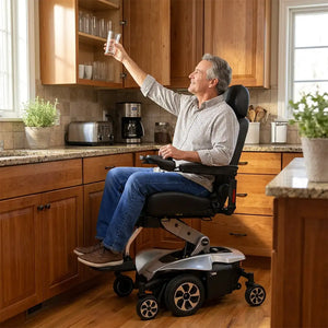 Usuario alcanzando un vaso con ayuda de la silla de ruedas eléctrica con compartimento bajo el asiento para transportar objetos personales con comodidad dortomedical