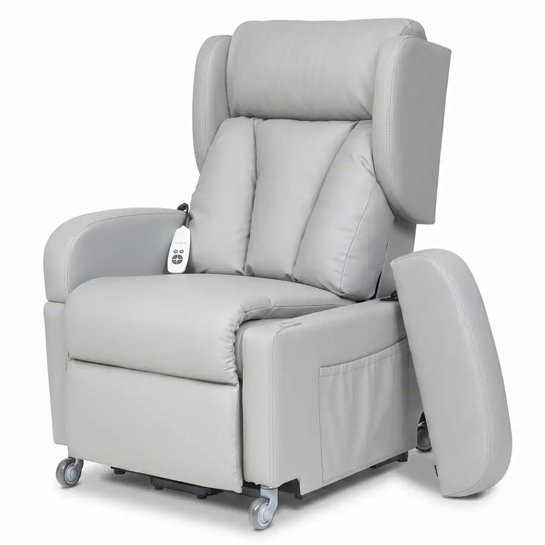 Vista frontal del sillón con el reposabrazos extraído y apoyado en el suelo, mostrando cómo se libera el lateral para realizar transferencias cómodas a sillas de ruedas o camas dortomedical