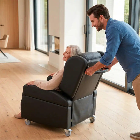 Un joven traslada el sillón fácilmente gracias al asa de empuje ergonómica y las ruedas con freno, facilitando la movilidad del paciente dentro de casa dortomedical